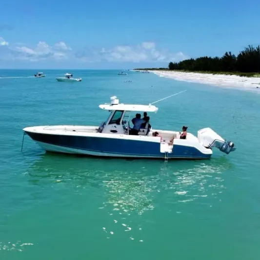  Yacht Photos Pics 2021 Boston Whaler 330 Outrage boat cruising near a scenic beach.