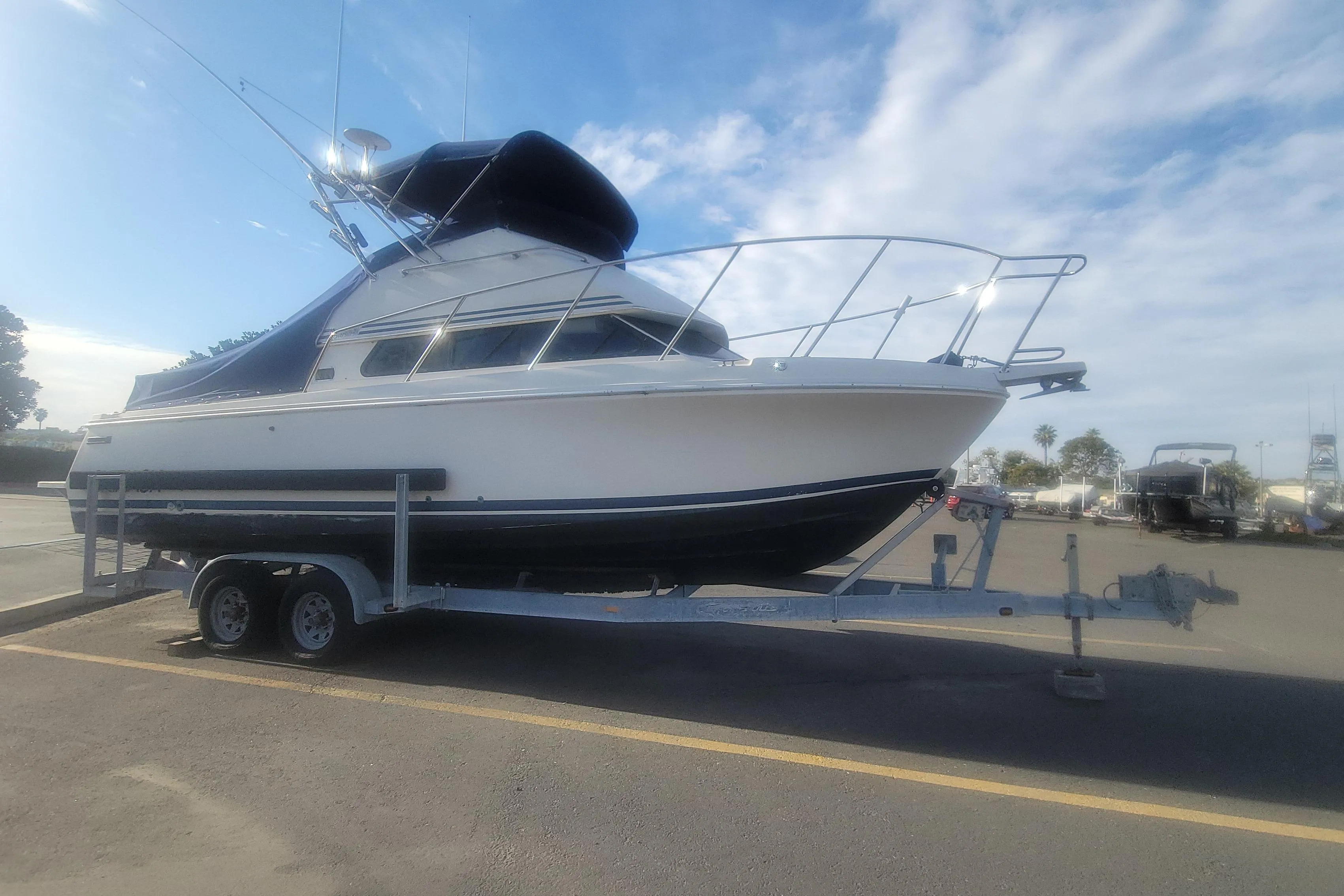 1997 Skipjack 262 Flybridge boat on trailer under a clear sky.