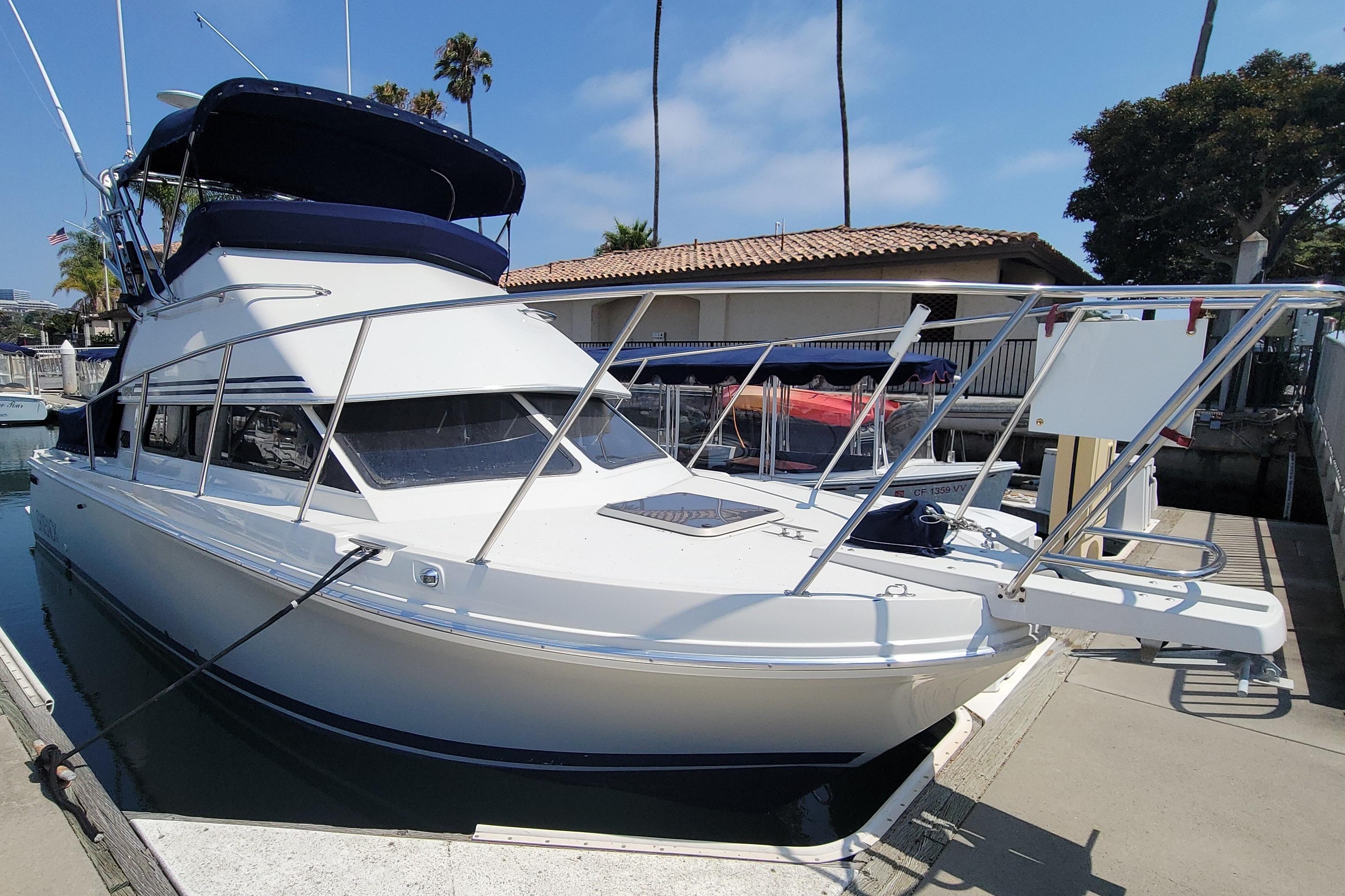 1997 Skipjack 262 Flybridge boat docked at marina under clear sky.