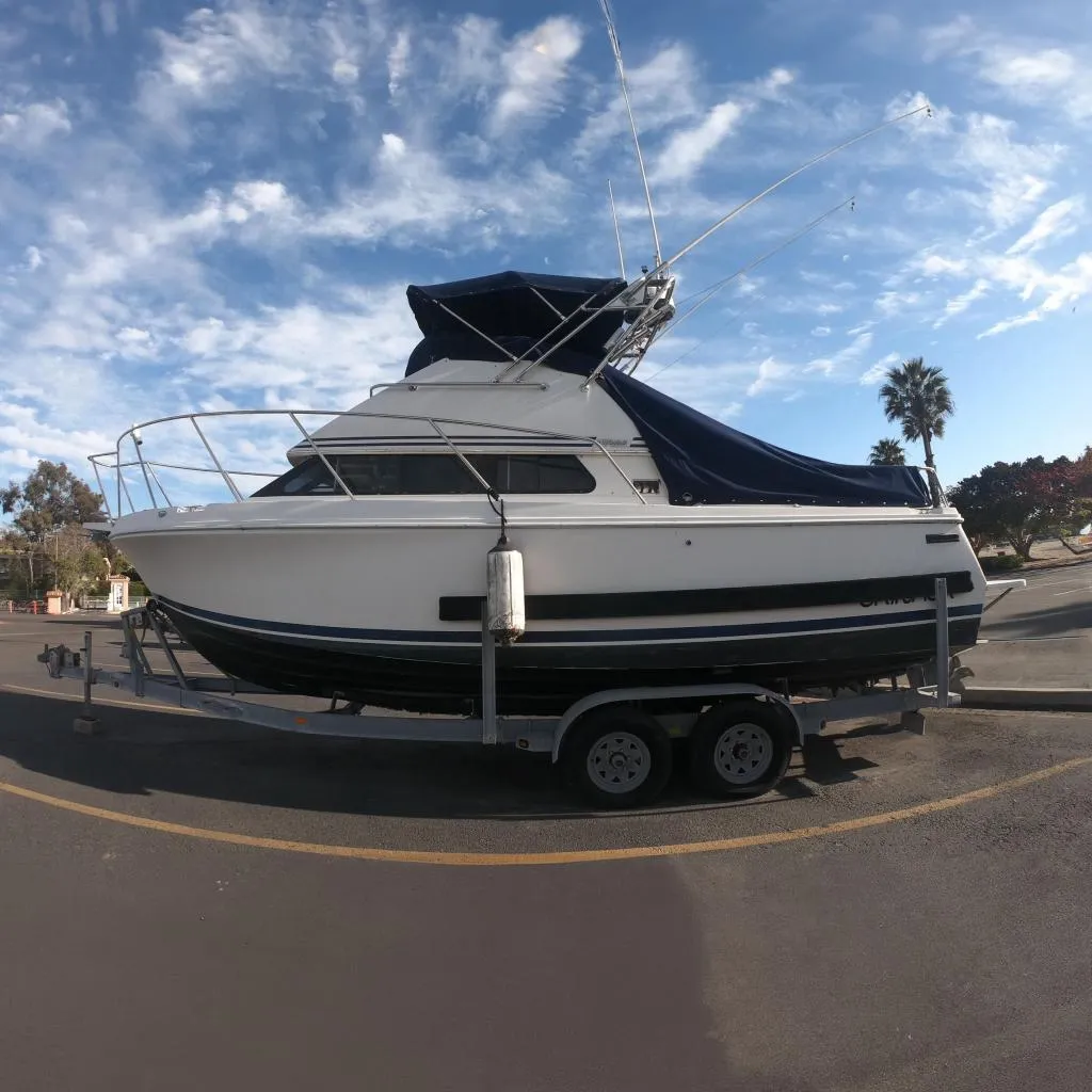 1997 Skipjack 262 Flybridge boat on trailer under clear blue sky.