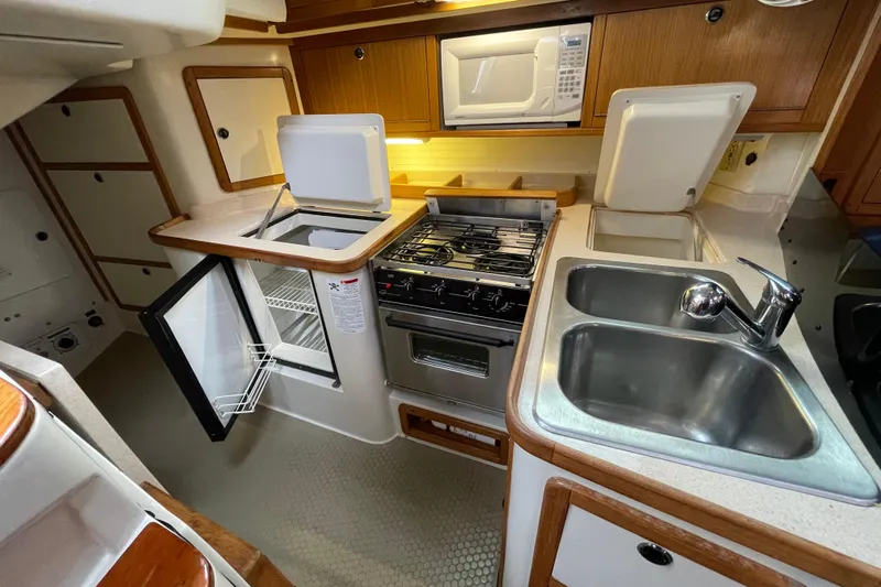 Buena Vida Yacht Photos Pics Compact kitchen in a 2000 Catalina 42 MkII yacht with stove, sink, and storage.