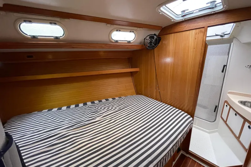 Buena Vida Yacht Photos Pics Cozy cabin interior of 2000 Catalina 42 MkII sailboat with striped bedding and wooden accents.