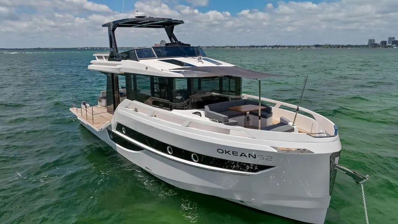  Yacht Photos Pics 2024 OKEAN 52 yacht cruising on clear blue waters under a partly cloudy sky.