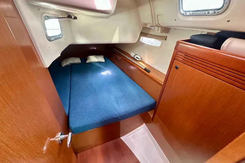  Yacht Photos Pics Cabin interior of 2010 Beneteau Oceanis 40 with blue bedding and wooden finish.