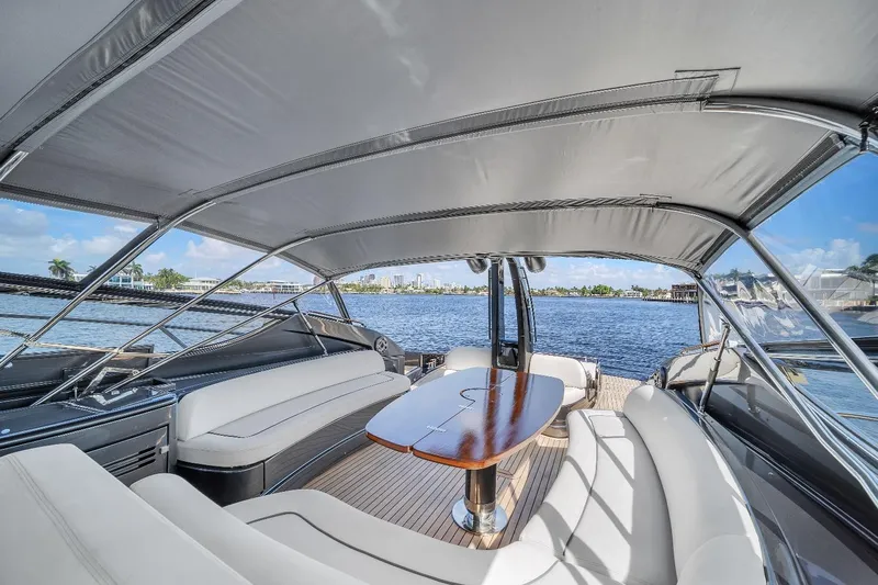 Joe Yacht Photos Pics 2015 Riva 63 Virtus yacht interior with elegant seating and table, overlooking serene water views.