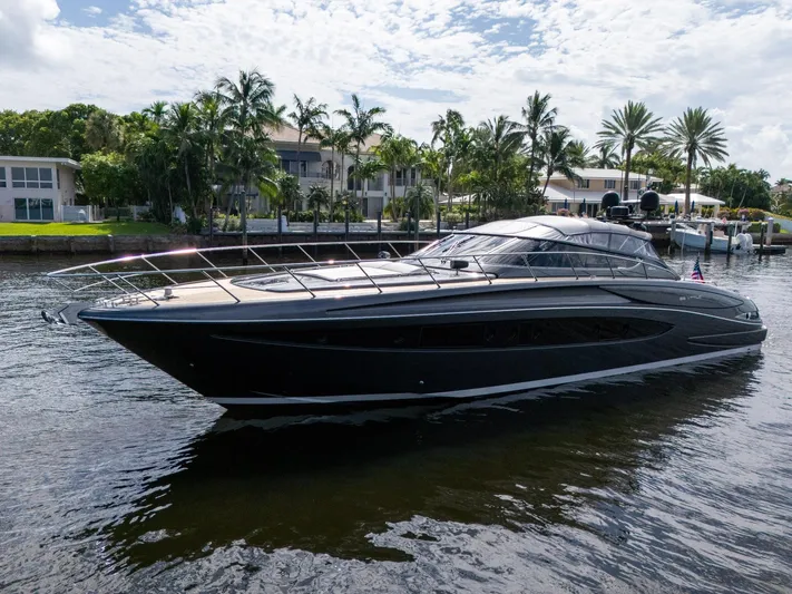 Joe Yacht Photos Pics 2015 Riva 63 Virtus yacht on a serene waterway, surrounded by lush palm trees.
