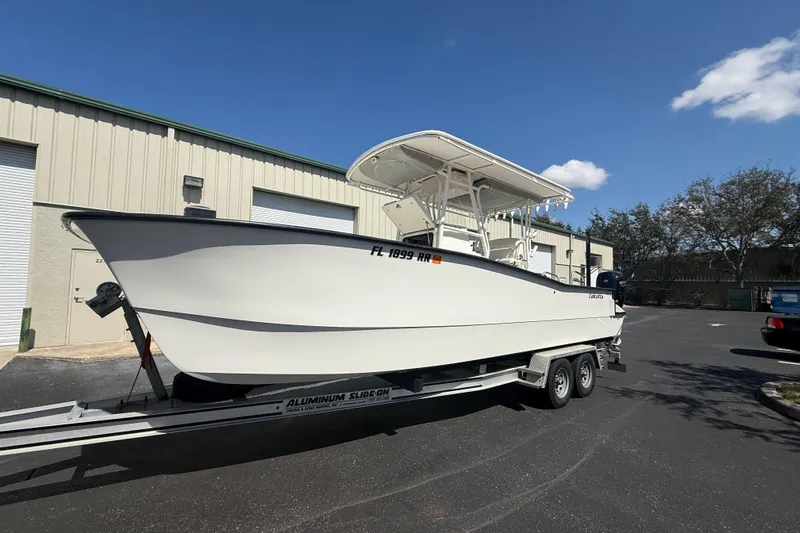  Yacht Photos Pics 2019 Calcutta 263 boat on trailer, parked outside a warehouse under clear blue sky.