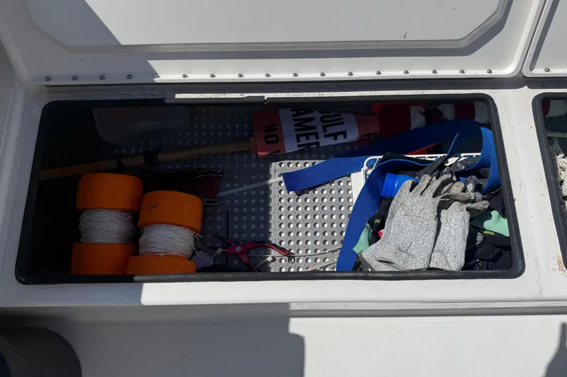  Yacht Photos Pics Storage compartment in a 2019 Calcutta 263 boat with ropes, gloves, and safety gear.