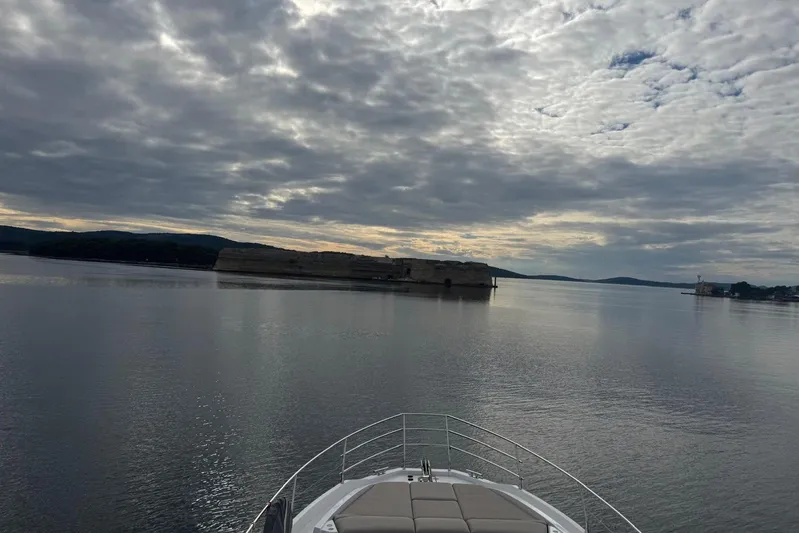  Yacht Photos Pics Bow of 2024 Azimut Fly 53 yacht cruising towards a scenic island under cloudy skies.