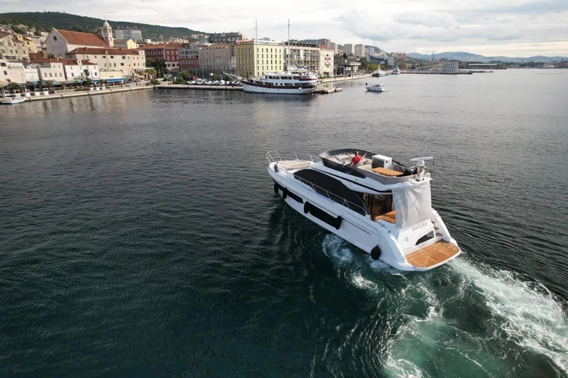  Yacht Photos Pics 2024 Azimut Fly 53 yacht cruising near a coastal cityscape.