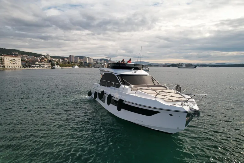  Yacht Photos Pics 2024 Azimut Fly 53 yacht cruising on a calm sea near a coastal city.