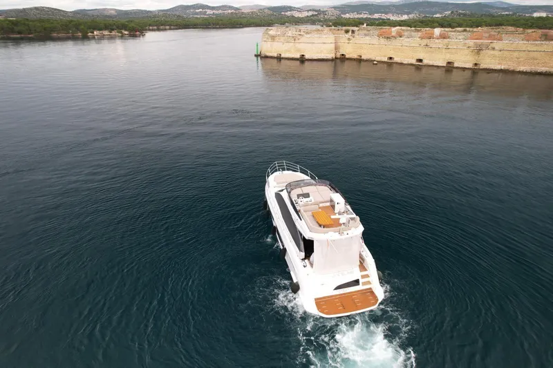  Yacht Photos Pics 2024 Azimut Fly 53 yacht cruising near a stone wall on calm waters.