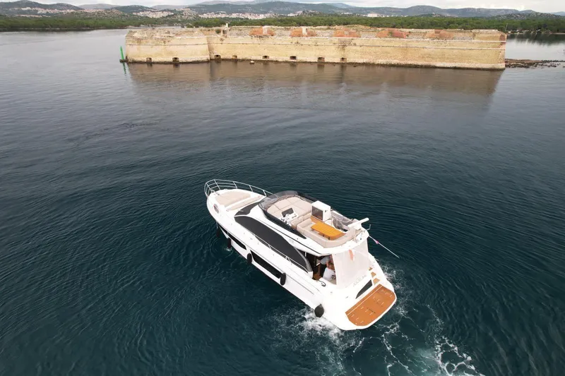  Yacht Photos Pics 2024 Azimut Fly 53 yacht cruising near a historic stone fort on calm waters.
