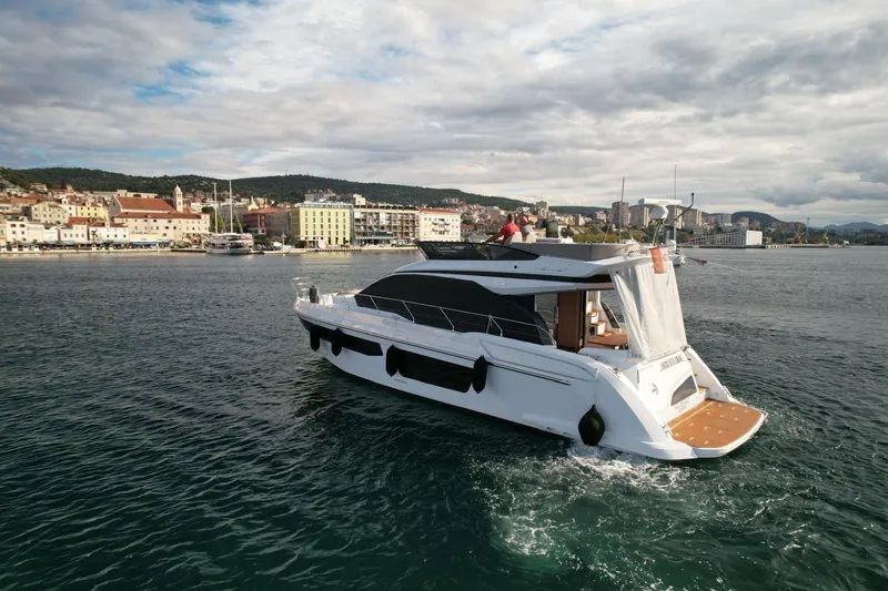  Yacht Photos Pics 2024 Azimut Fly 53 yacht cruising near a coastal city under cloudy skies.