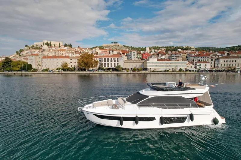  Yacht Photos Pics 2024 Azimut Fly 53 yacht cruising near a scenic coastal town.
