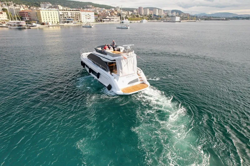  Yacht Photos Pics 2024 Azimut Fly 53 yacht cruising in scenic coastal waters near a cityscape.