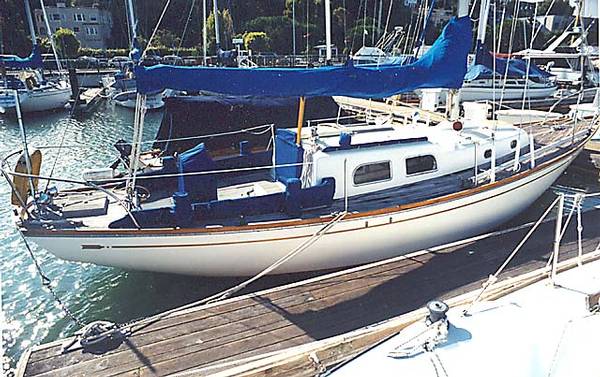 1965 Pearson Vanguard sailboat docked at a marina, featuring a blue cover and classic design.