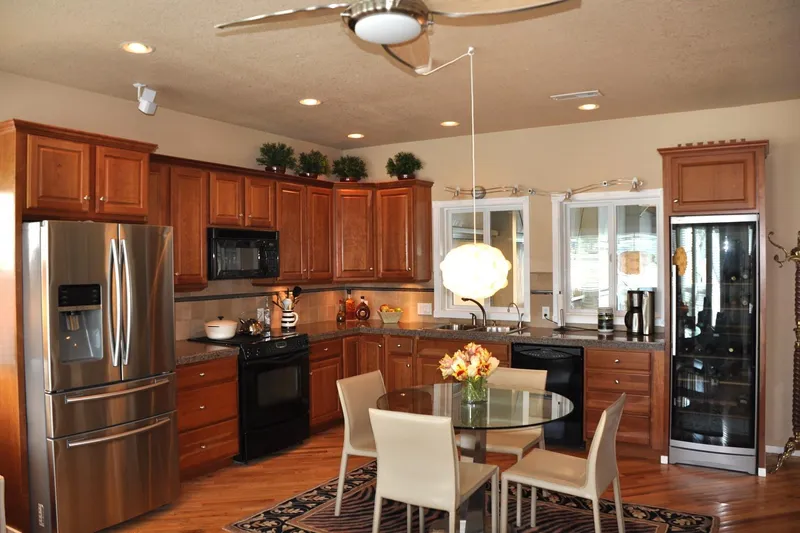  Yacht Photos Pics Modern kitchen with wooden cabinets, stainless steel appliances, and a round glass dining table.