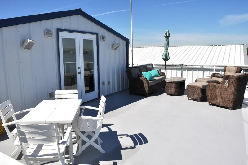  Yacht Photos Pics Rooftop patio on 2004 Steelhead Marine Boat House with outdoor furniture and umbrella.