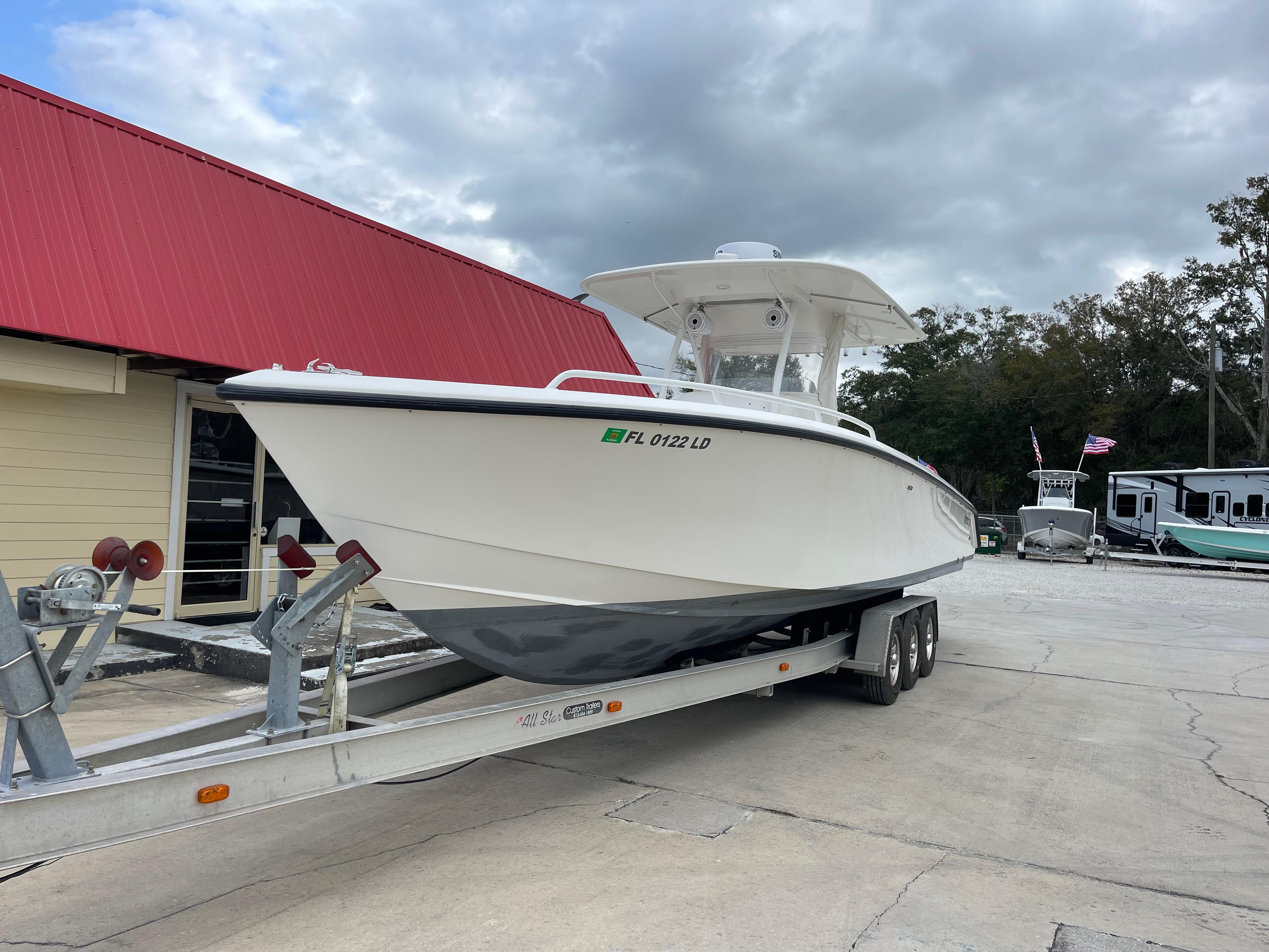 1999 Venture 34 Center Console boat on a trailer near a red-roofed building.