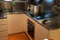 Kitchen interior of a 2008 Pershing 90 yacht with modern appliances and wooden flooring.