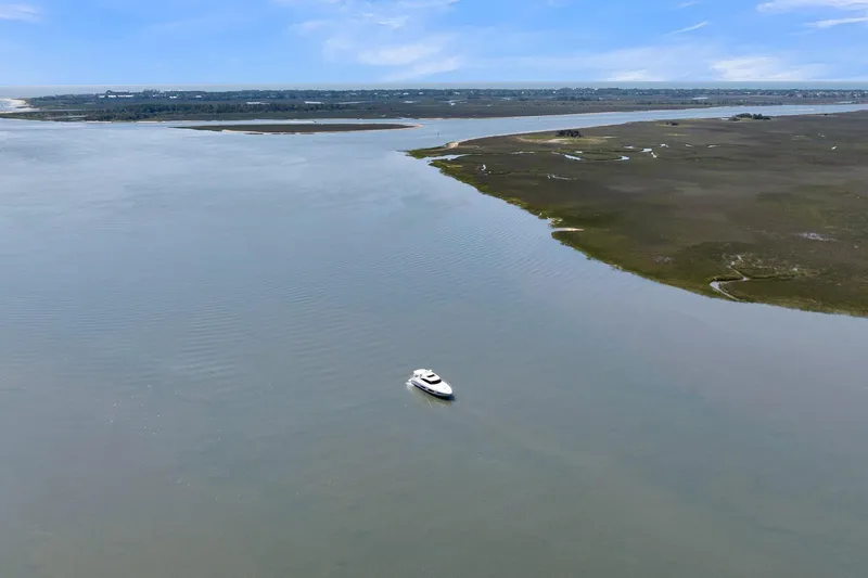  Yacht Photos Pics Aerial view of 2020 Riviera 4800 Sport Yacht on calm waters near a coastal landscape.