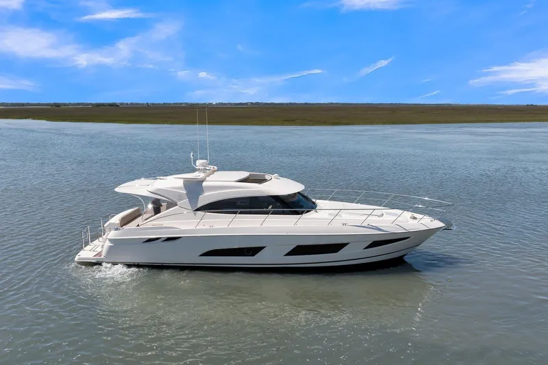 Yacht Photos Pics 2020 Riviera 4800 Sport Yacht cruising on calm waters under a clear blue sky.