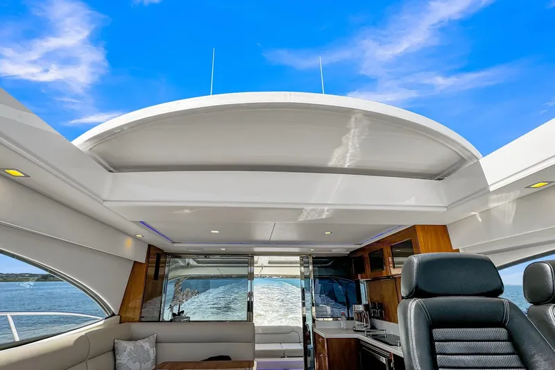  Yacht Photos Pics Interior view of 2020 Riviera 4800 Sport Yacht with open roof and ocean backdrop.