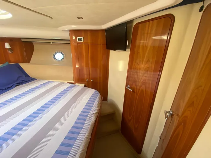  Yacht Photos Pics Luxurious cabin interior of 2006 Cranchi Mediterranee 47 yacht with wood finish and striped bedding.