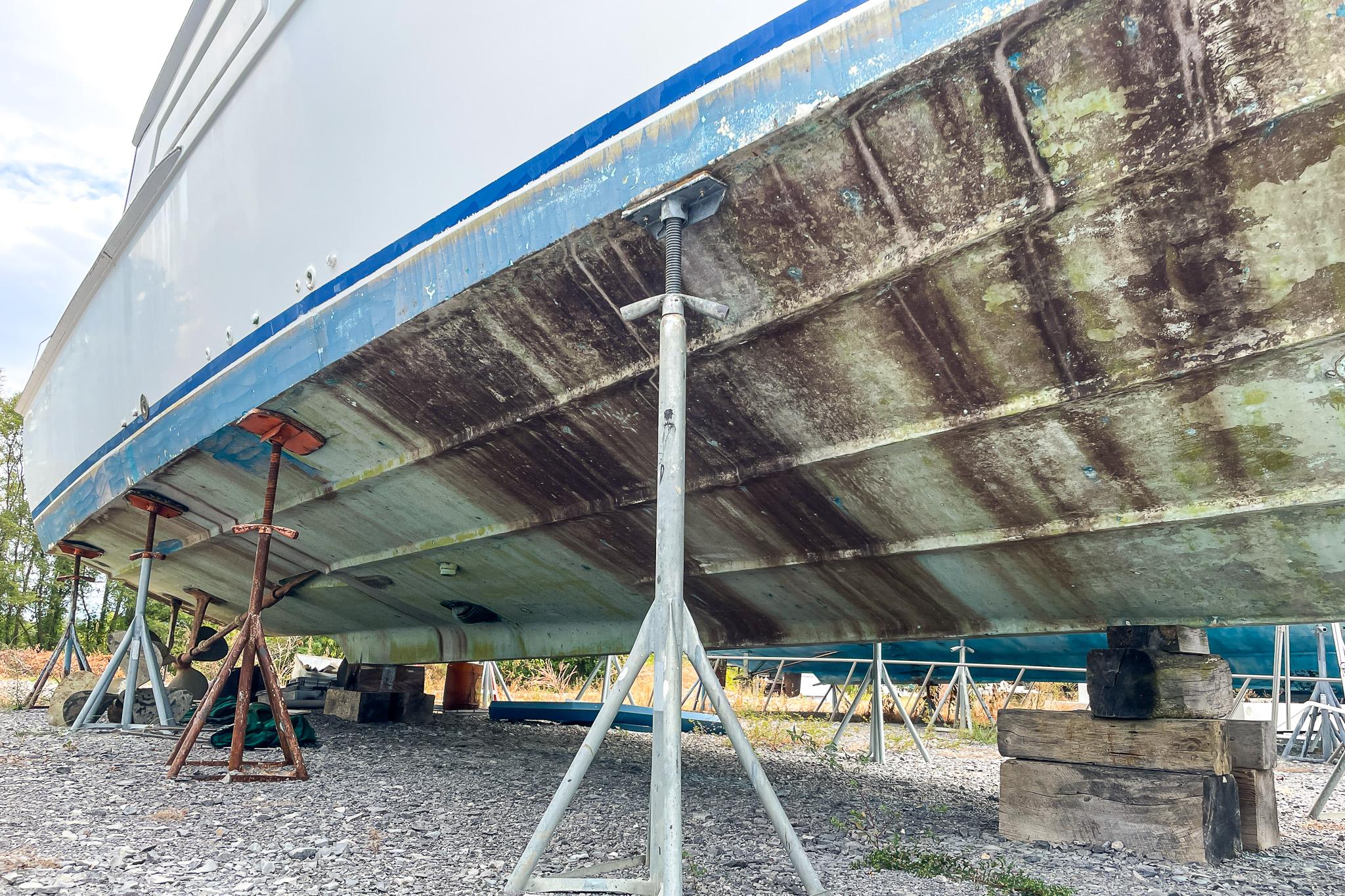 1978 Bertram 46 Convertible boat hull on stands, showing weathered underside.