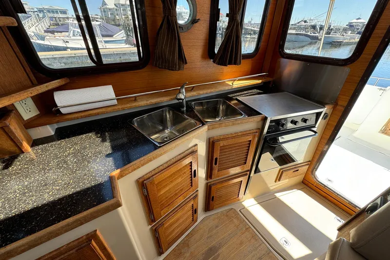 Point Aft'r Yacht Photos Pics Interior of 2012 Ranger Tugs R-29 boat kitchen with sink, stove, and wooden cabinets.