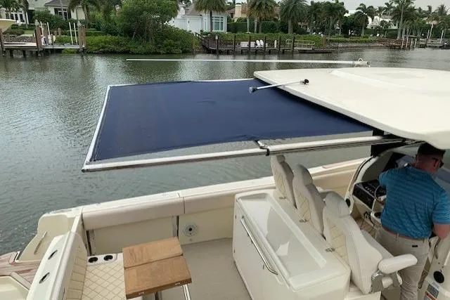  Yacht Photos Pics 2020 Chris-Craft Catalina 34 boat with extended sunshade, docked by a scenic waterfront.
