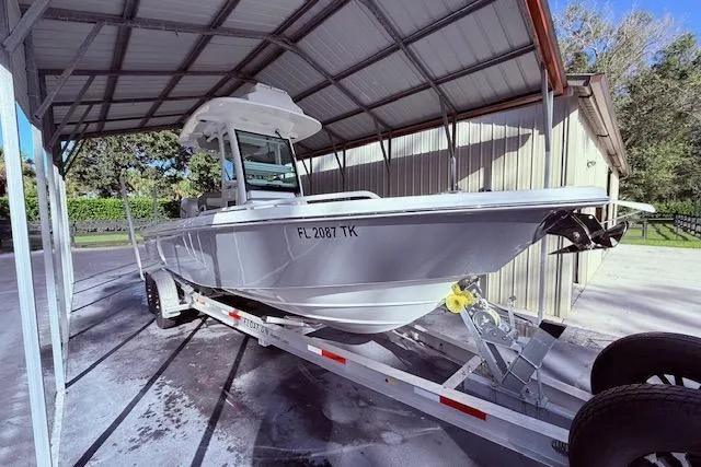 Yacht Photos Pics 2023 Everglades 253 Center Console boat on trailer under metal canopy.