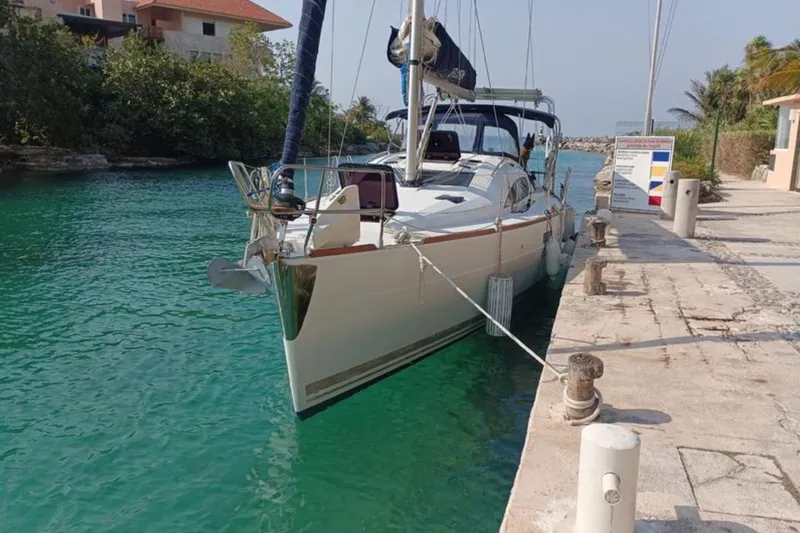  Yacht Photos Pics 2018 Elan Impression 40 yacht docked in a serene, turquoise canal setting.