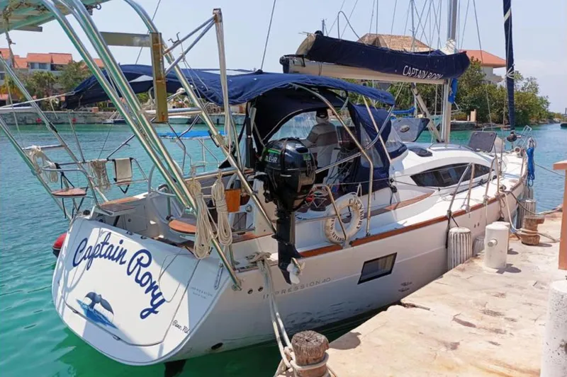  Yacht Photos Pics 2018 Elan Impression 40 yacht docked, named "Captain Roxy," with blue canopy and scenic backdrop.