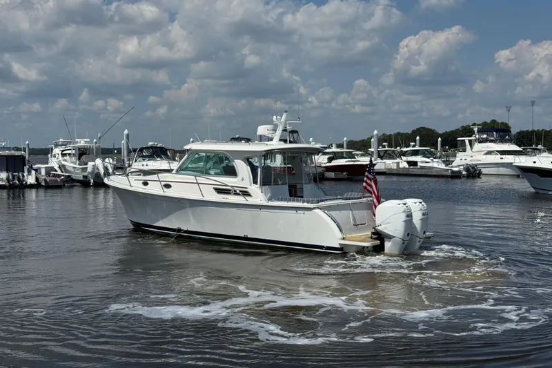  Yacht Photos Pics 2022 Back Cove 34O boat in marina, surrounded by other vessels, under a partly cloudy sky.