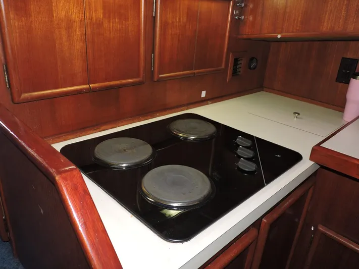  Yacht Photos Pics 1990 Post 44 Sport Fisherman kitchen with electric stovetop and wooden cabinetry.