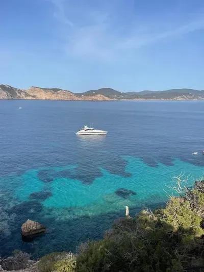  Yacht Photos Pics Luxury Mangusta 80 yacht on serene blue waters, 2006 model, with scenic coastal backdrop.