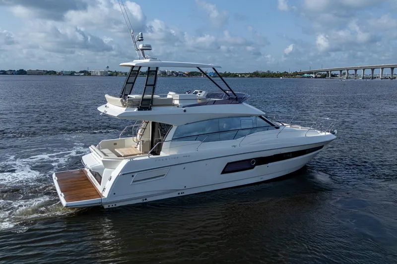 Pamper You Yacht Photos Pics 2019 Prestige 460 yacht cruising on a calm river under a cloudy sky.