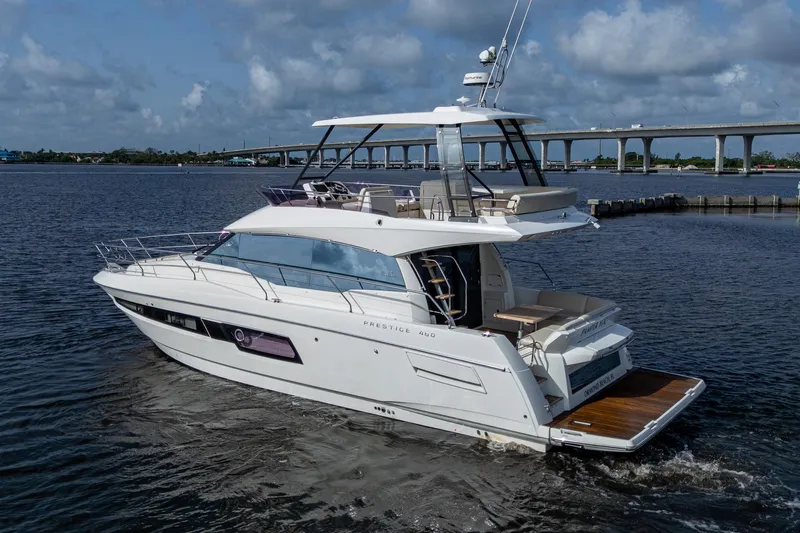 Pamper You Yacht Photos Pics 2019 Prestige 460 yacht cruising on a calm river under a cloudy sky.
