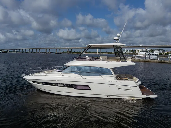 Pamper You Yacht Photos Pics 2019 Prestige 460 yacht cruising on a calm river under a cloudy sky.