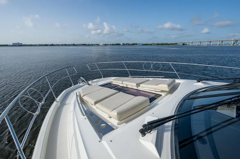 Pamper You Yacht Photos Pics 2019 Prestige 460 yacht with sun loungers on deck, overlooking calm waters and distant bridge.