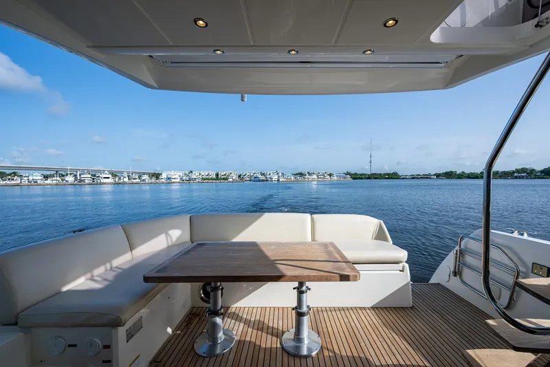 Pamper You Yacht Photos Pics Prestige 460 yacht deck with seating and table, overlooking serene water view.