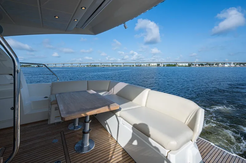Pamper You Yacht Photos Pics Luxury yacht deck with seating and table, Prestige 460, 2019 model, overlooking serene waters.