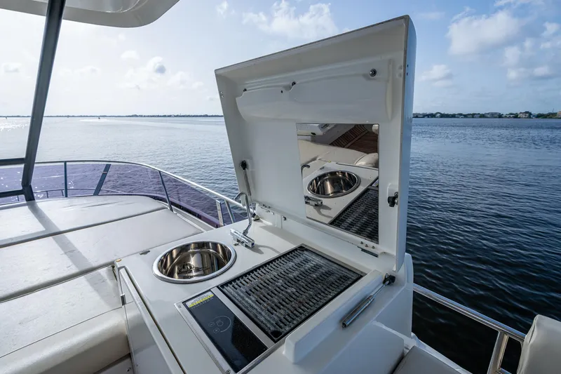Pamper You Yacht Photos Pics Outdoor kitchen on 2019 Prestige 460 yacht with grill and sink, overlooking serene water.