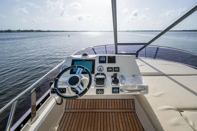 Pamper You Yacht Photos Pics Helm of 2019 Prestige 460 yacht with wooden deck, overlooking calm waters.