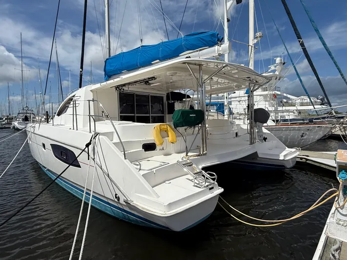 Merry Mac Yacht Photos Pics 2013 Leopard 44 catamaran docked at marina, featuring blue canopy and spacious deck.