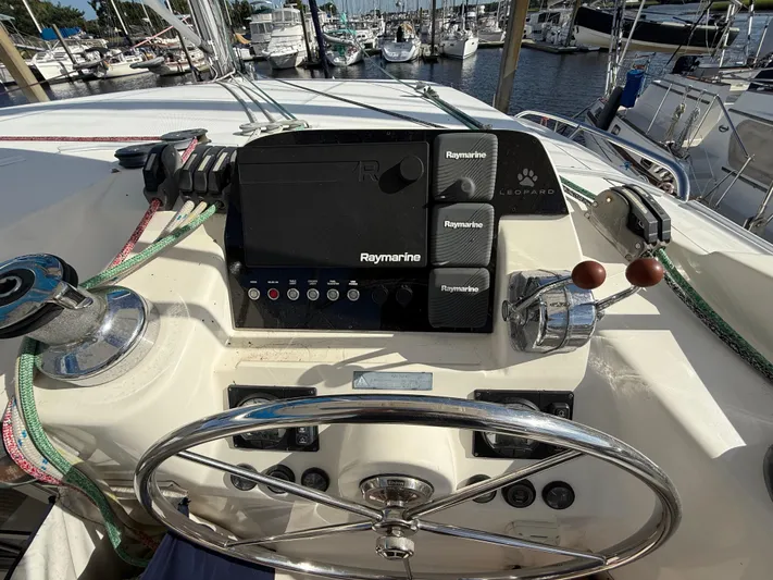Merry Mac Yacht Photos Pics Steering wheel and controls of a 2013 Leopard 44 yacht at a marina.