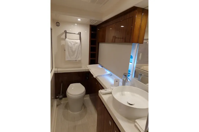 Mon Trésor Yacht Photos Pics Luxurious bathroom in 2020 Riviera 6000 Sport Yacht Platinum Edition, featuring modern fixtures and elegant wood cabinetry.