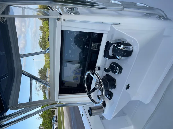 Reel Chaos Yacht Photos Pics Control panel of a 2022 Bahama 35 Open boat with steering wheel and navigation display.